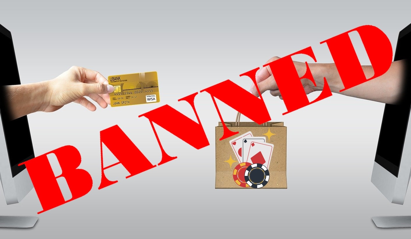 A hand stretches out with a credit card for online gambling, covered by a banned sign.