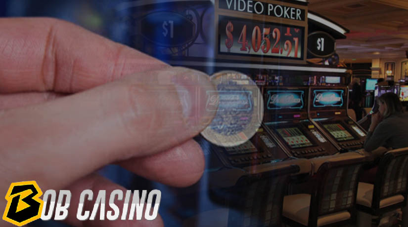 Man inserting a coin into the video poker machine